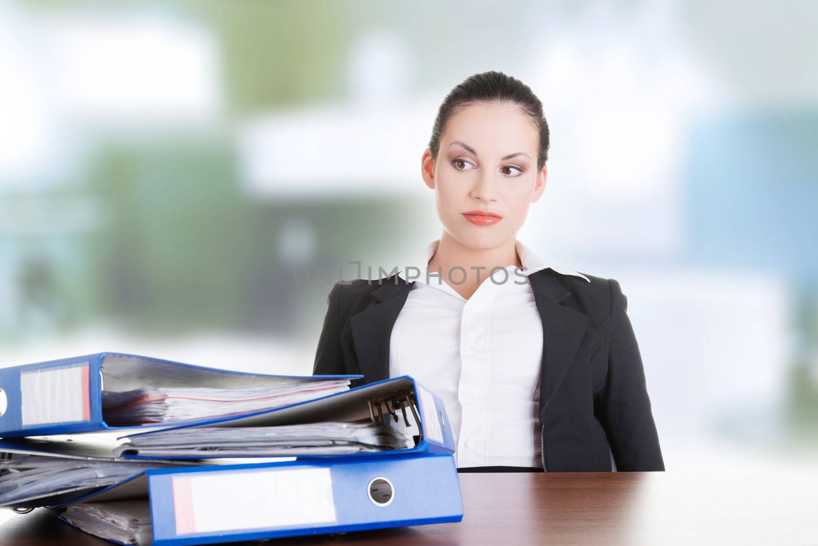 Sad woman with ringbinders sitting at the desk. Tired and exhousted business woman.