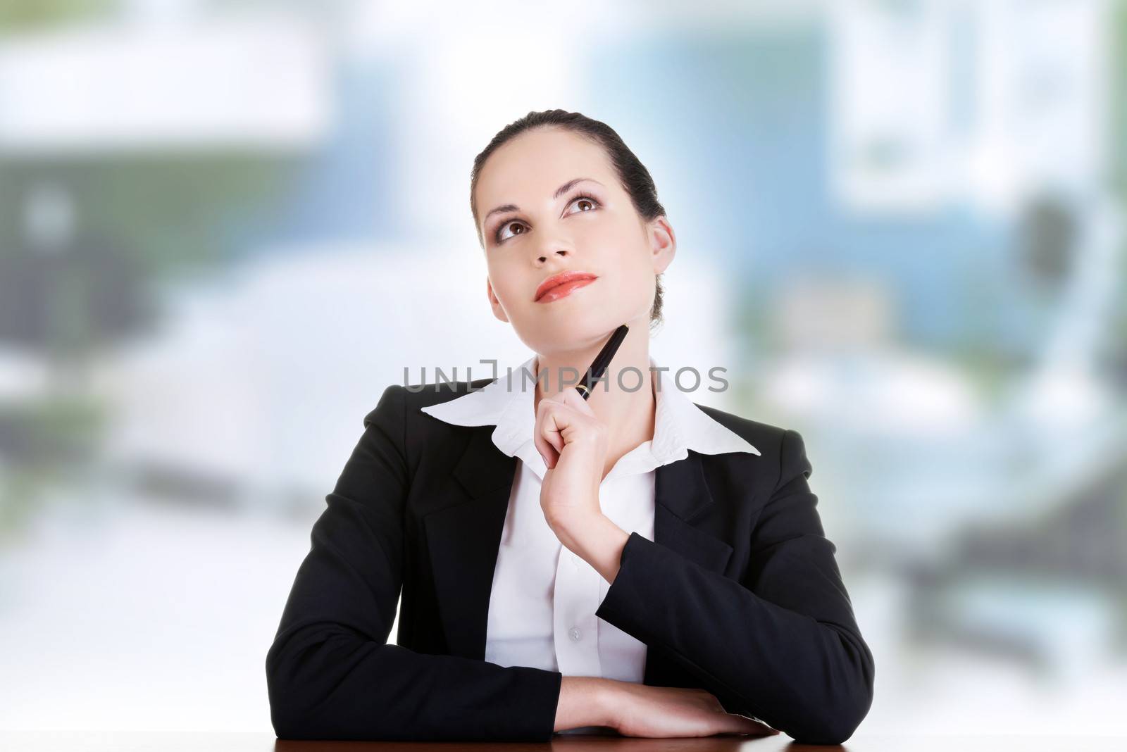 Pretty business woman in sitting at the desk and thinking, isolated on white