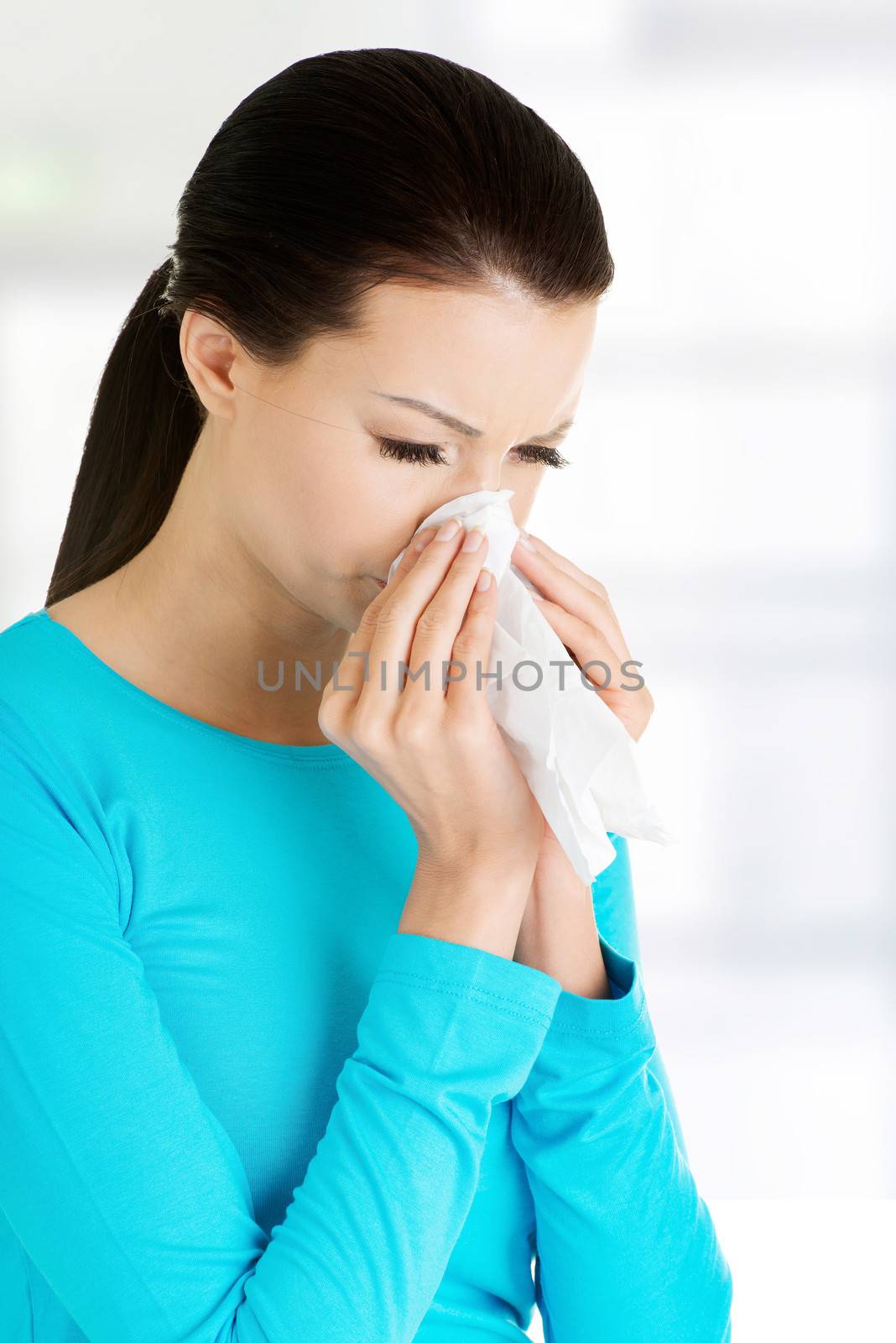 Young woman with tissue - sneezing. Allergy or cold.