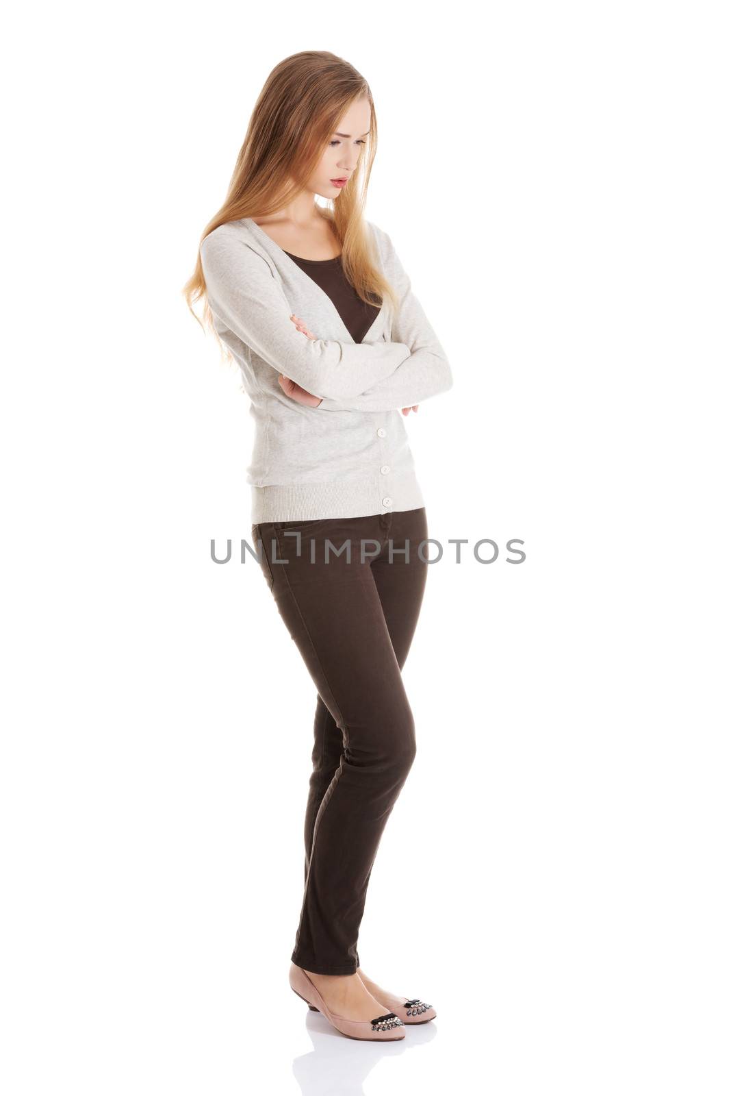 Beautiful woman is standing, lookis sad, with her hands crossed. Isolated on white.