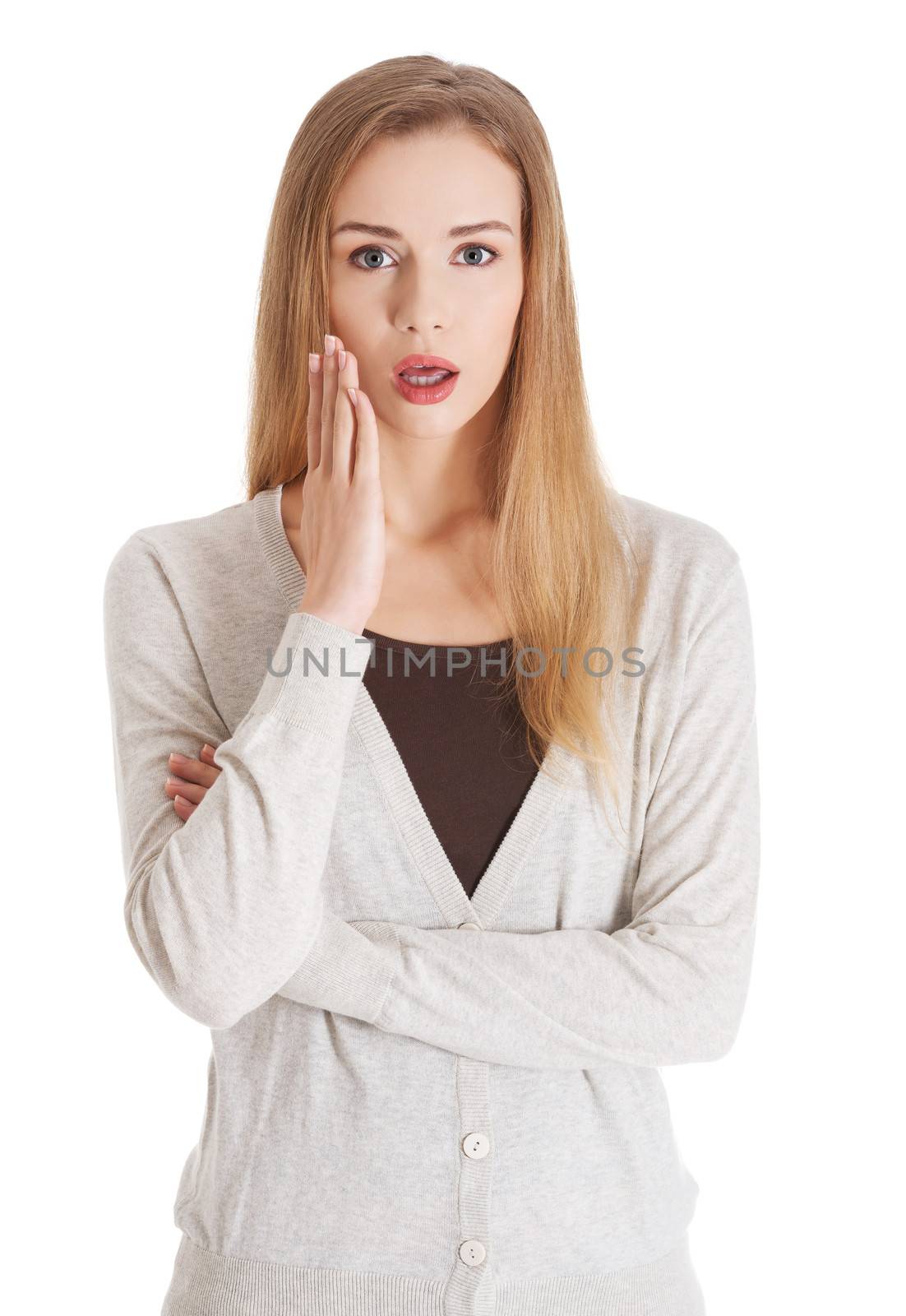 Beautiful casual woman with open mouth and hand next to face, expressing shock. Isolated on white.