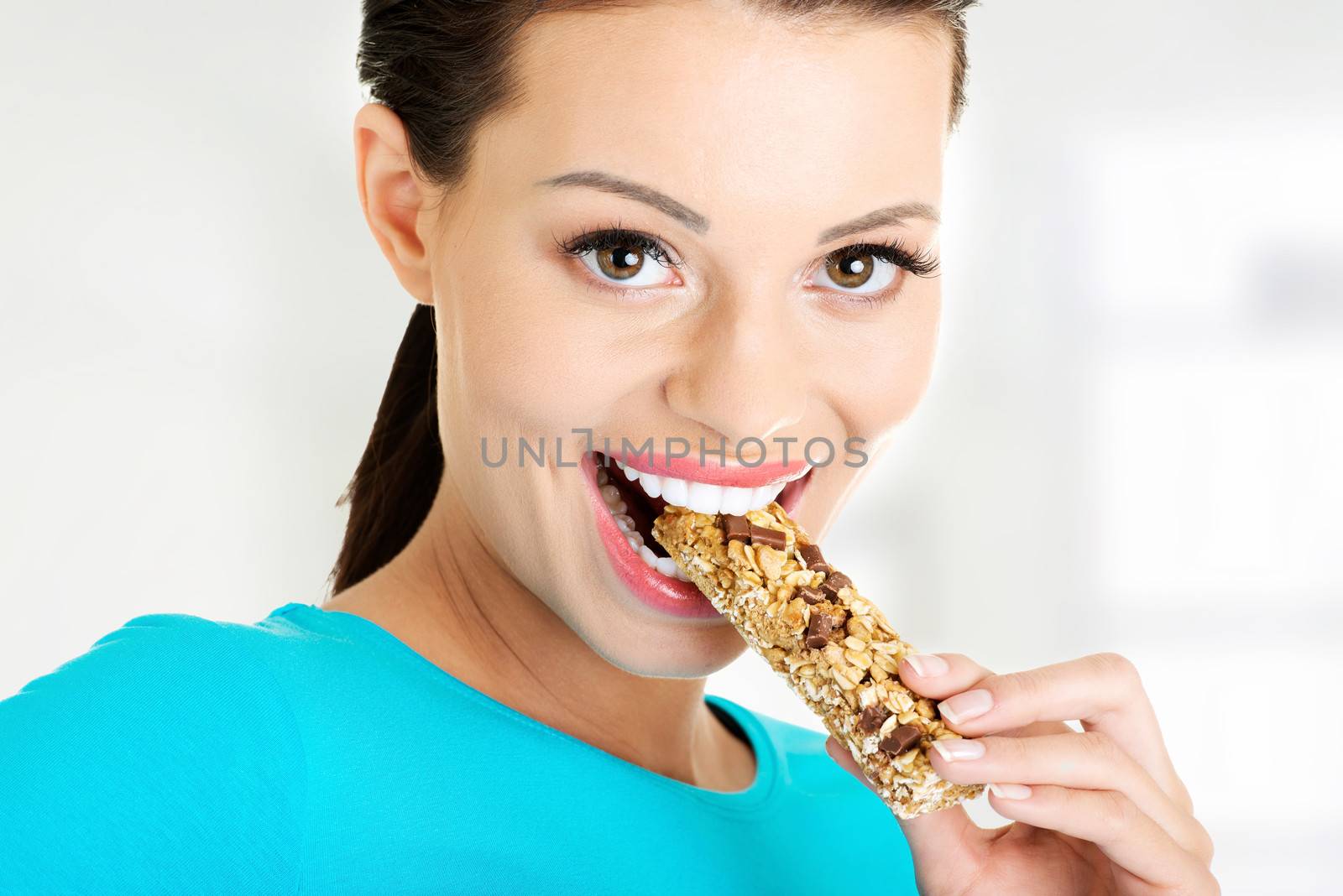 Young woman eating Cereal candy bar, isolated on white