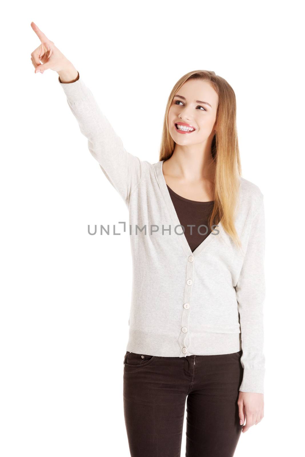 Beautiful casual woman is pointing up and advertising. Isolated on white.