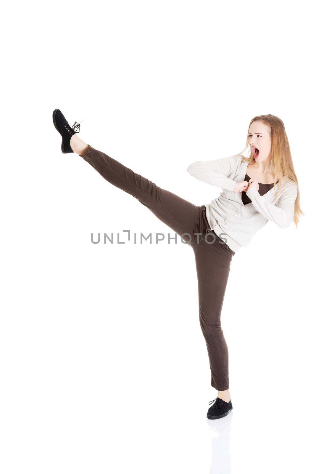 Beautiful casual woman doing a kick. Isolated on white.