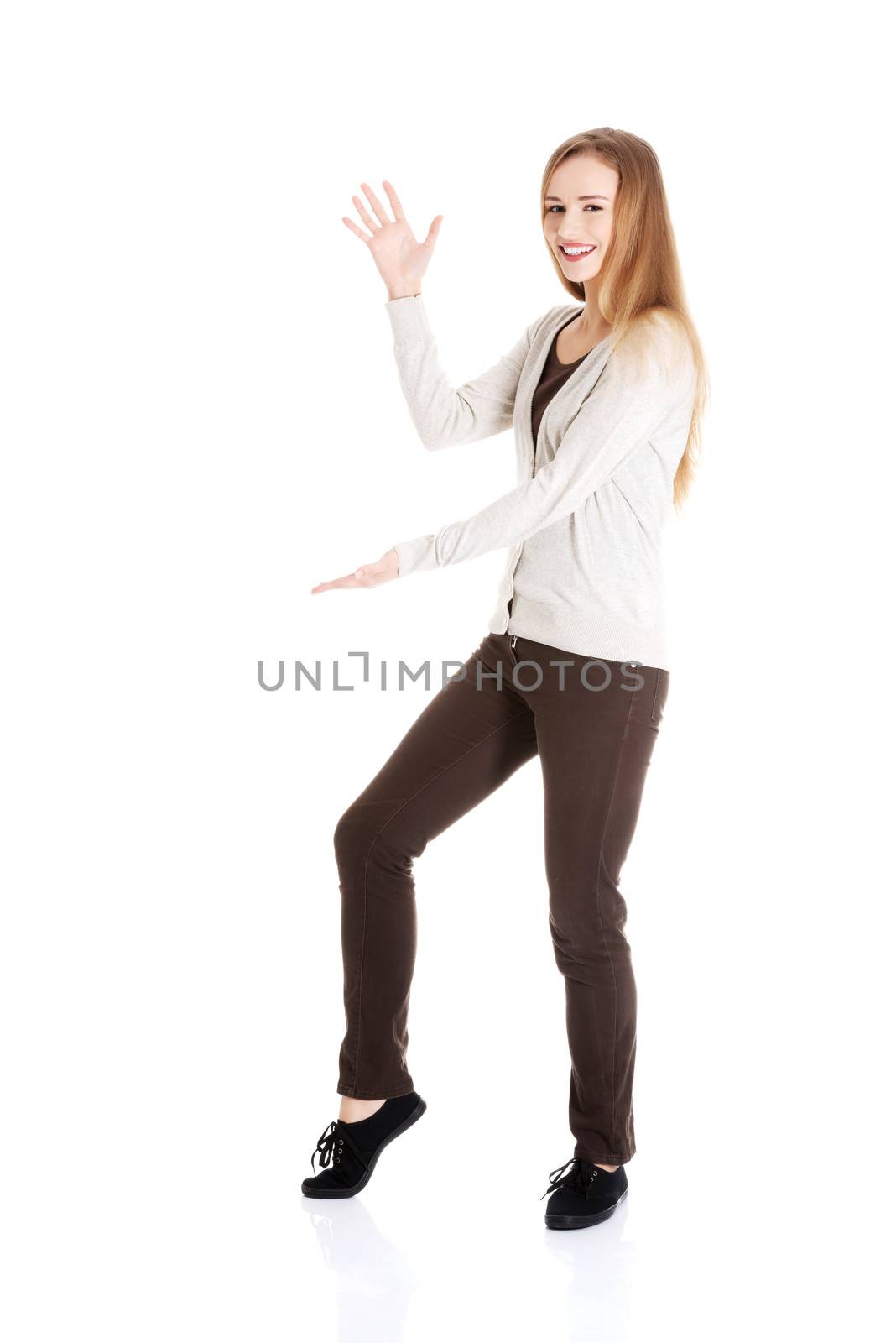 Beautiful casual woman posing with her hand up and leg. Isolated on white.