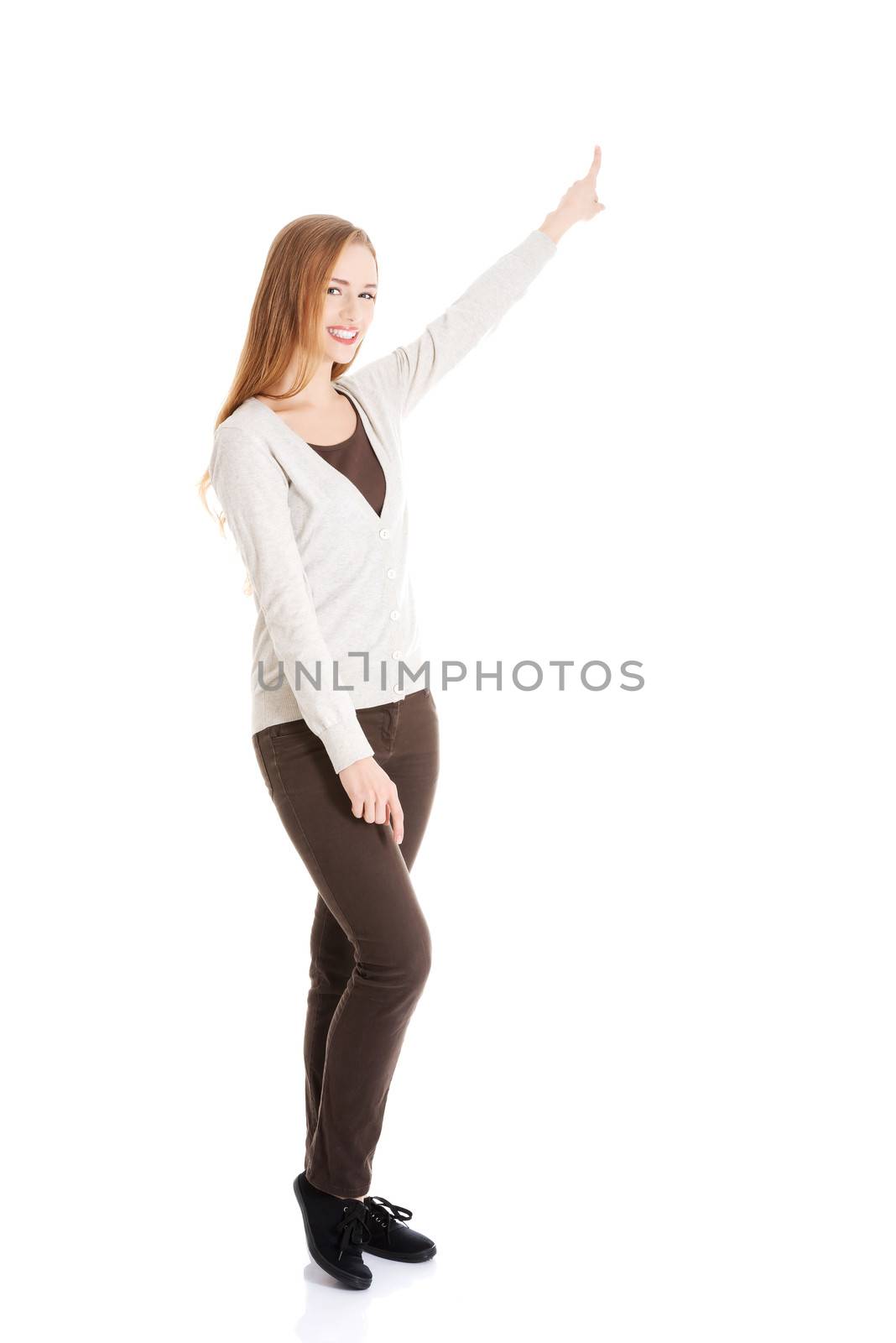 Beautiful casual woman pointing up and advertising. Isolated on white.
