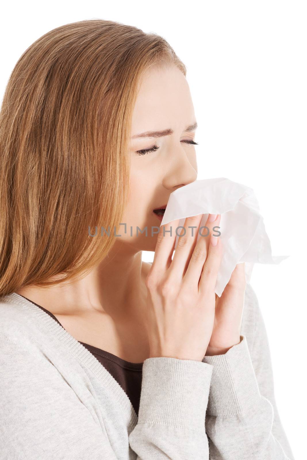 Beautiful woman sneezing, holding a tissue. Isolated on white.