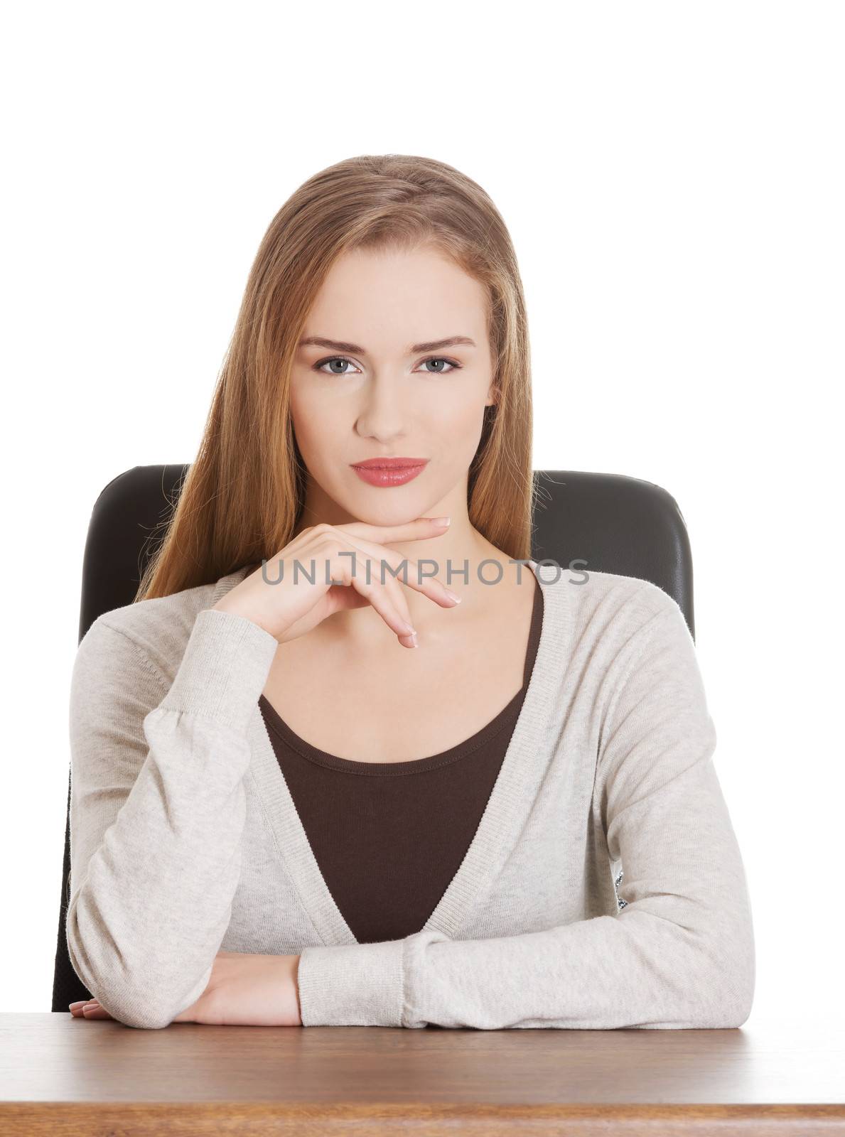 Beautiful casual woman sitting by a desk. Isolated on white.