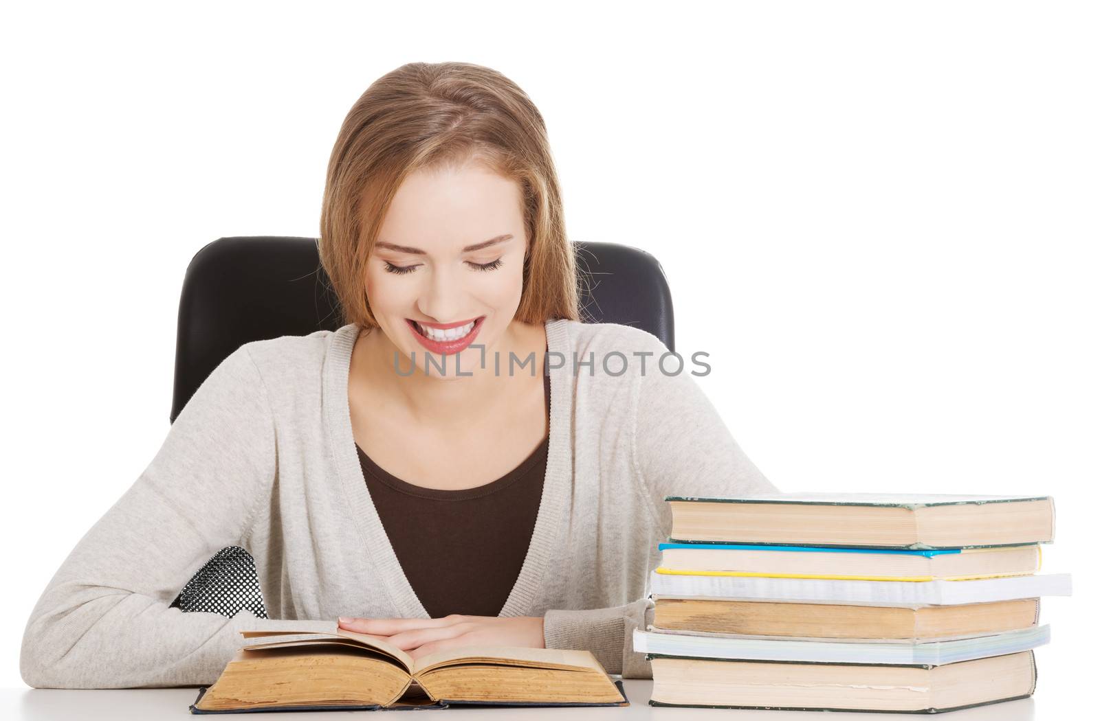 Beautiful student woman sitting by the desk with books and learning. Isolated on white.