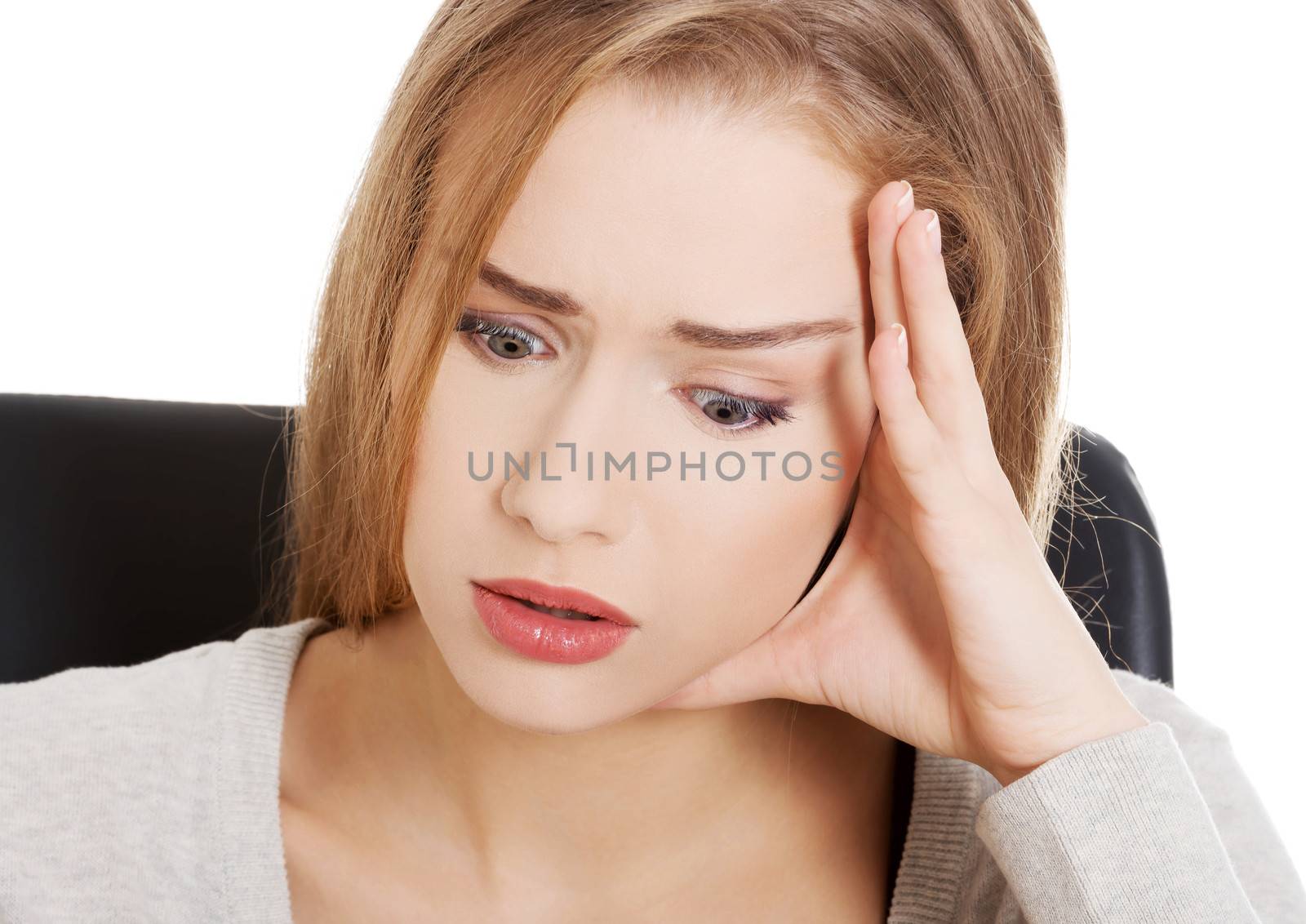 Beautiful casual woman student worried, scared is sitting by a desk and stack of books. Isolated on white.