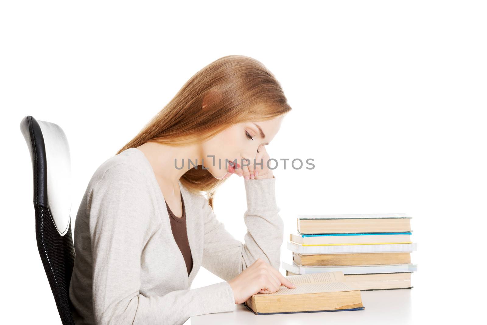 Bored and tired casual student woman sitting by the desk and learning. Isolated on white.