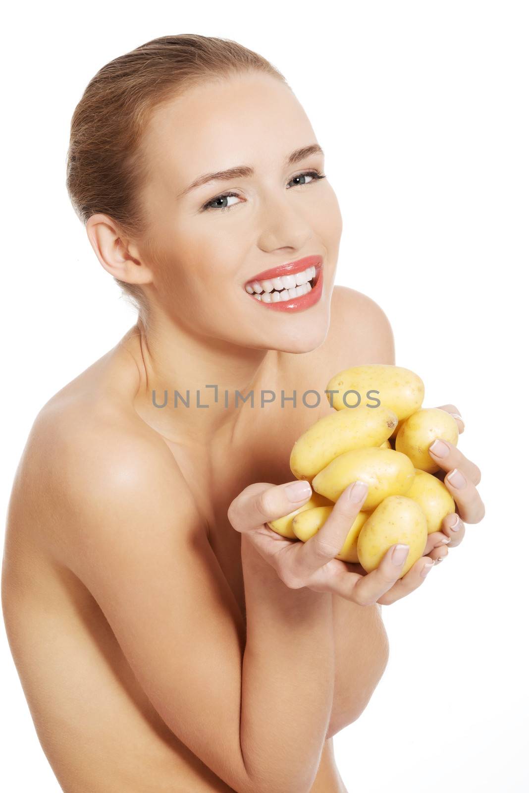 Beautiful naked caucasian woman is holding fresh, raw potatoes. Isolated on white.
