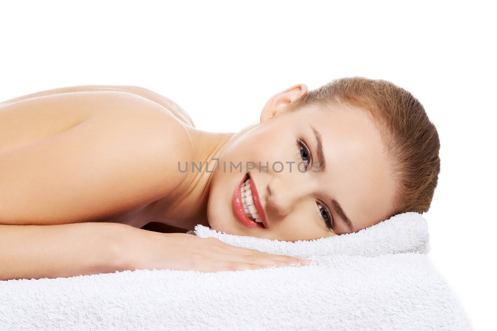 Beautiful caucasian naked woman lying on a massage table and relaxing. Isolated on white.