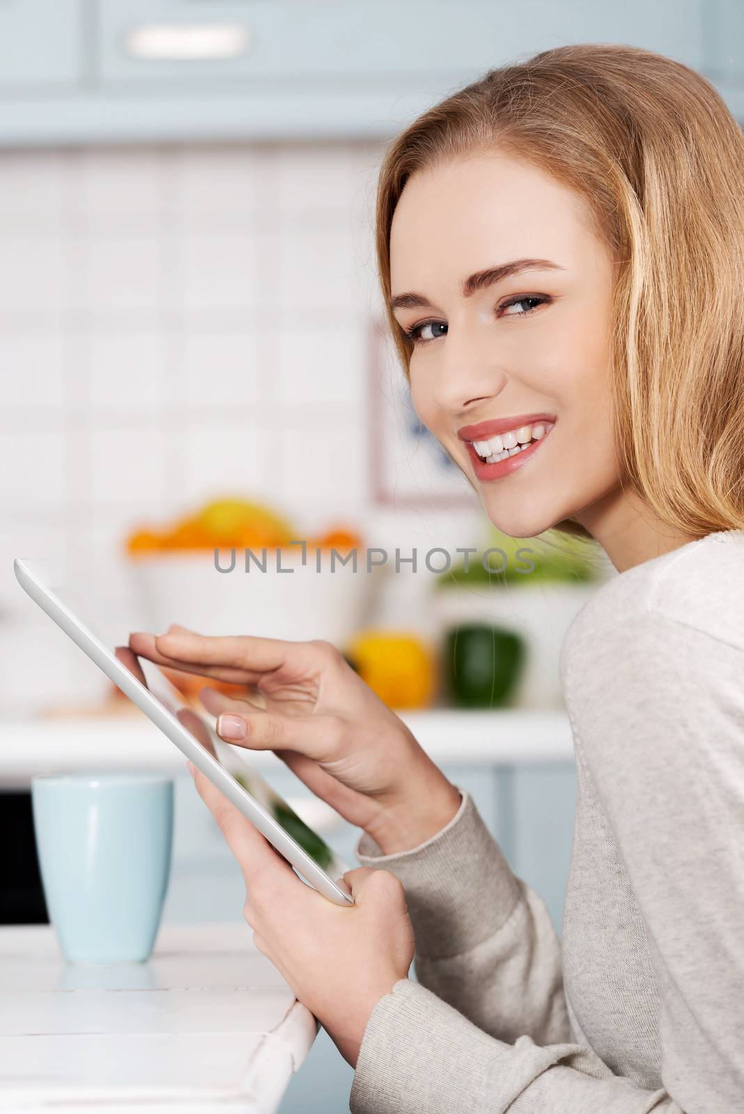 Beautiful caucasian woman holding tablet. Indoor background.