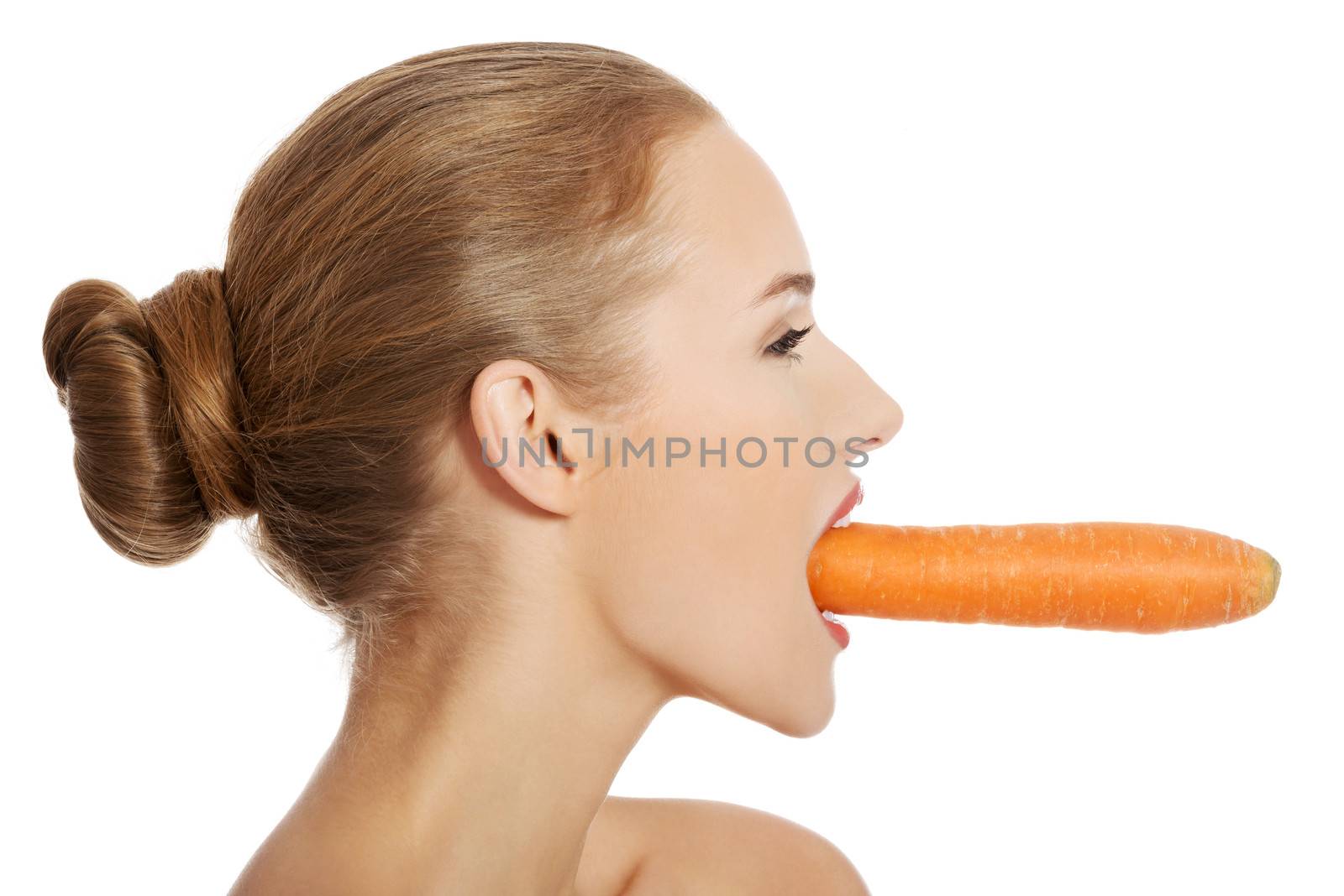 Beautiful profile of caucasian woman eating raw fresh carrot. Isolated on white.