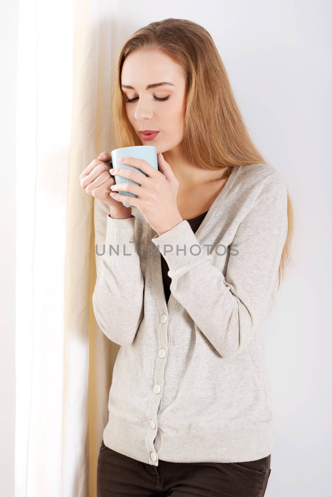 Beautiful casual caucasian woman standing by the window with hot by BDS