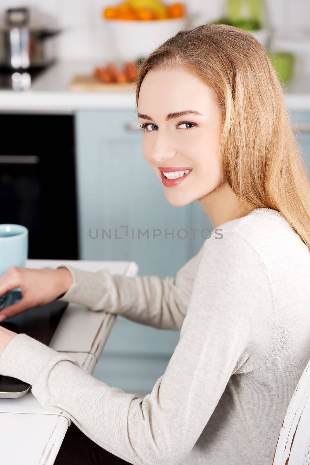 Young beautiful woman sitting by the table with laptop and cup. by BDS