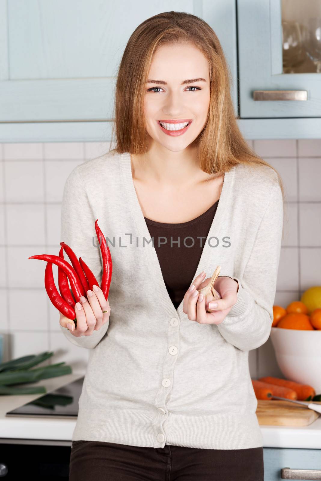 Beautiful caucasian woman is holding chili peppers and garlic. by BDS