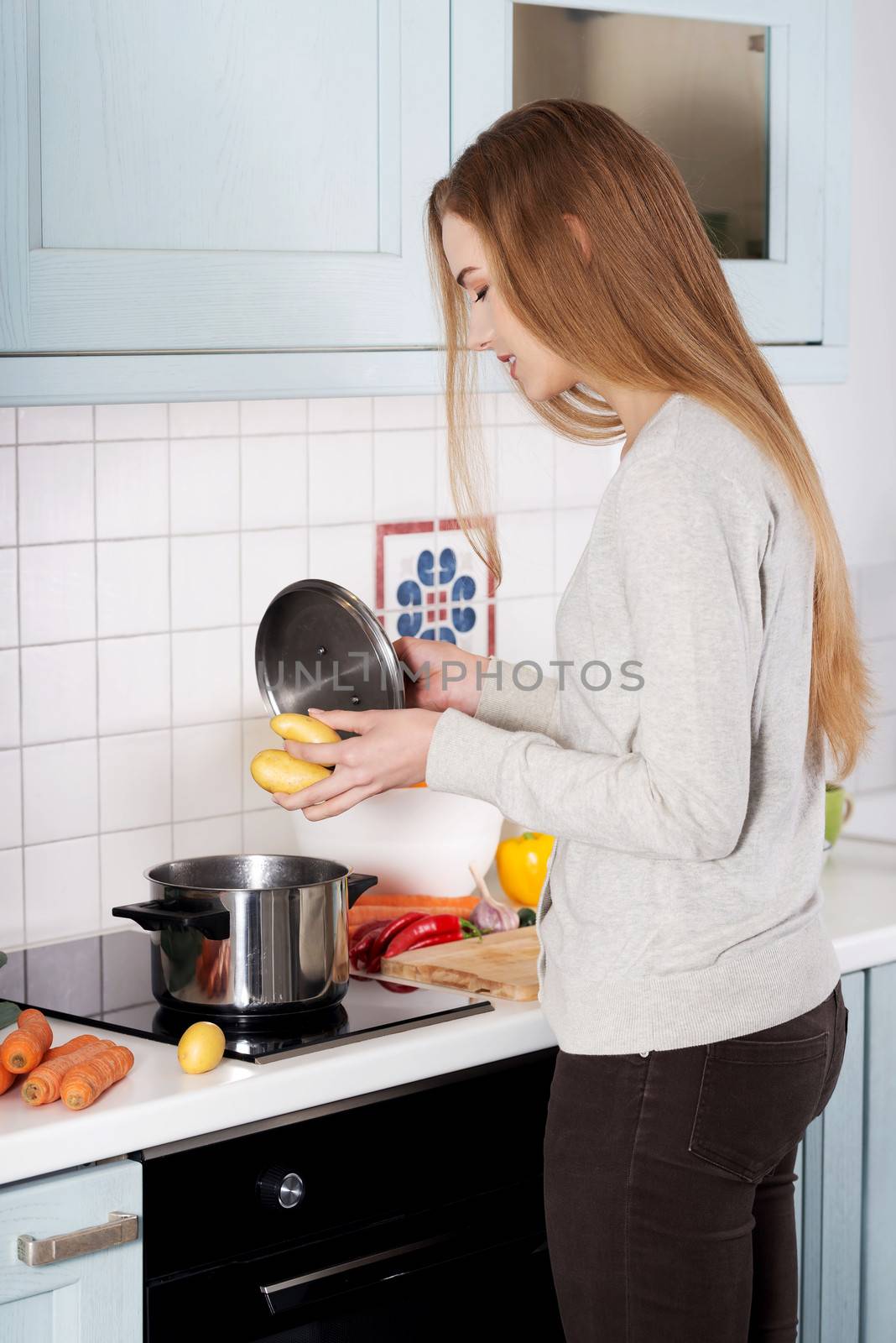 Beautiful young woman standing in the kitchen and preparing food.