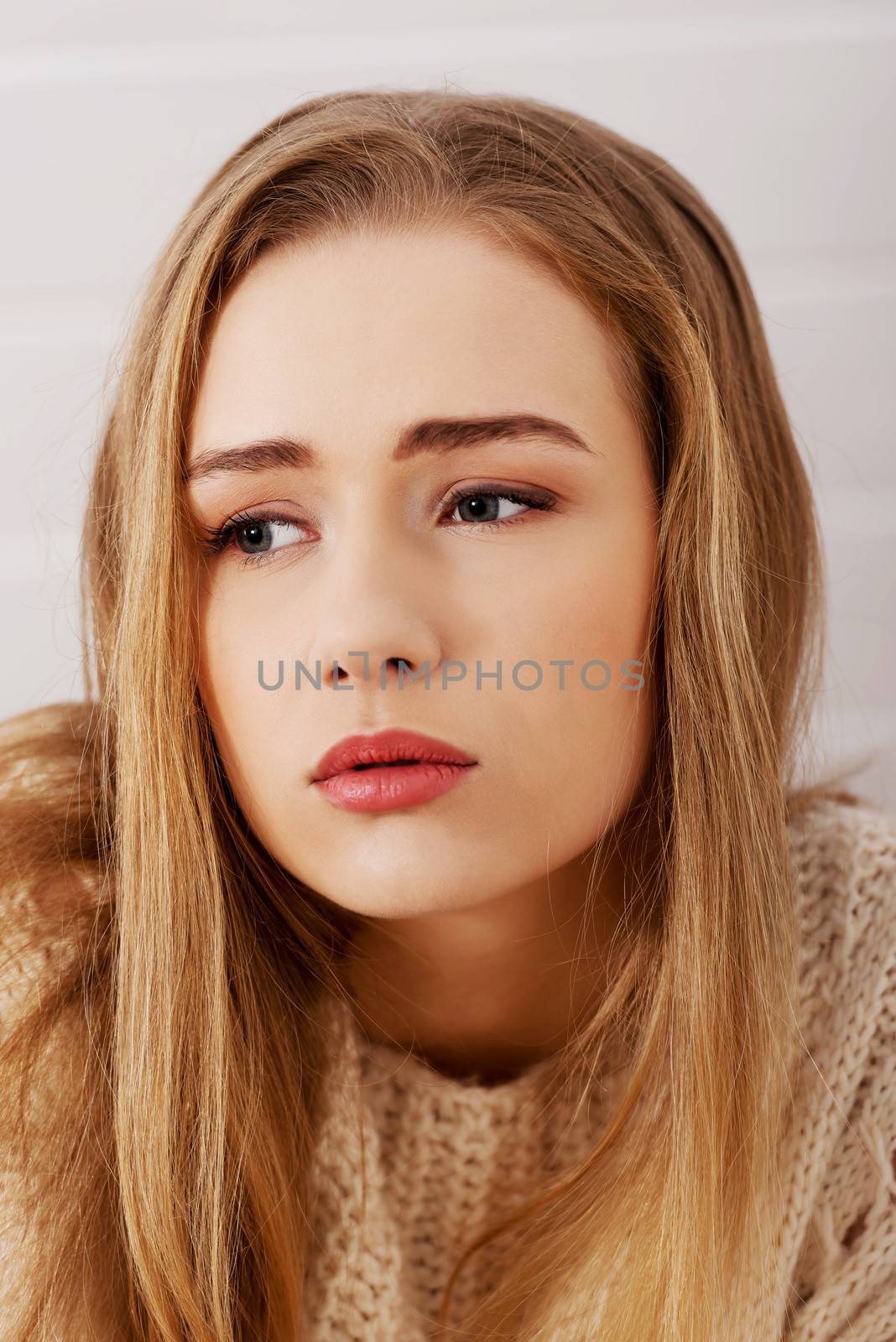 Portraif of beautiful sad, worried caucasian woman in bright sweater.