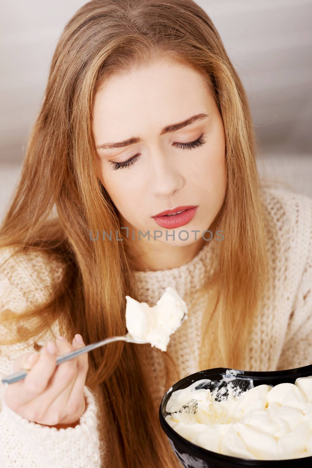 Young depressed woman is eating big bowl of ice creams to comfort herself. Depression, bulimia and diet concept.