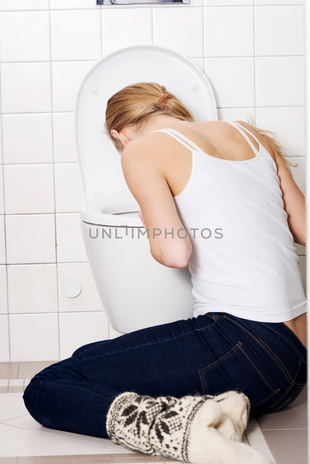 Young caucasian woman is vomiting in the bathroom. by BDS