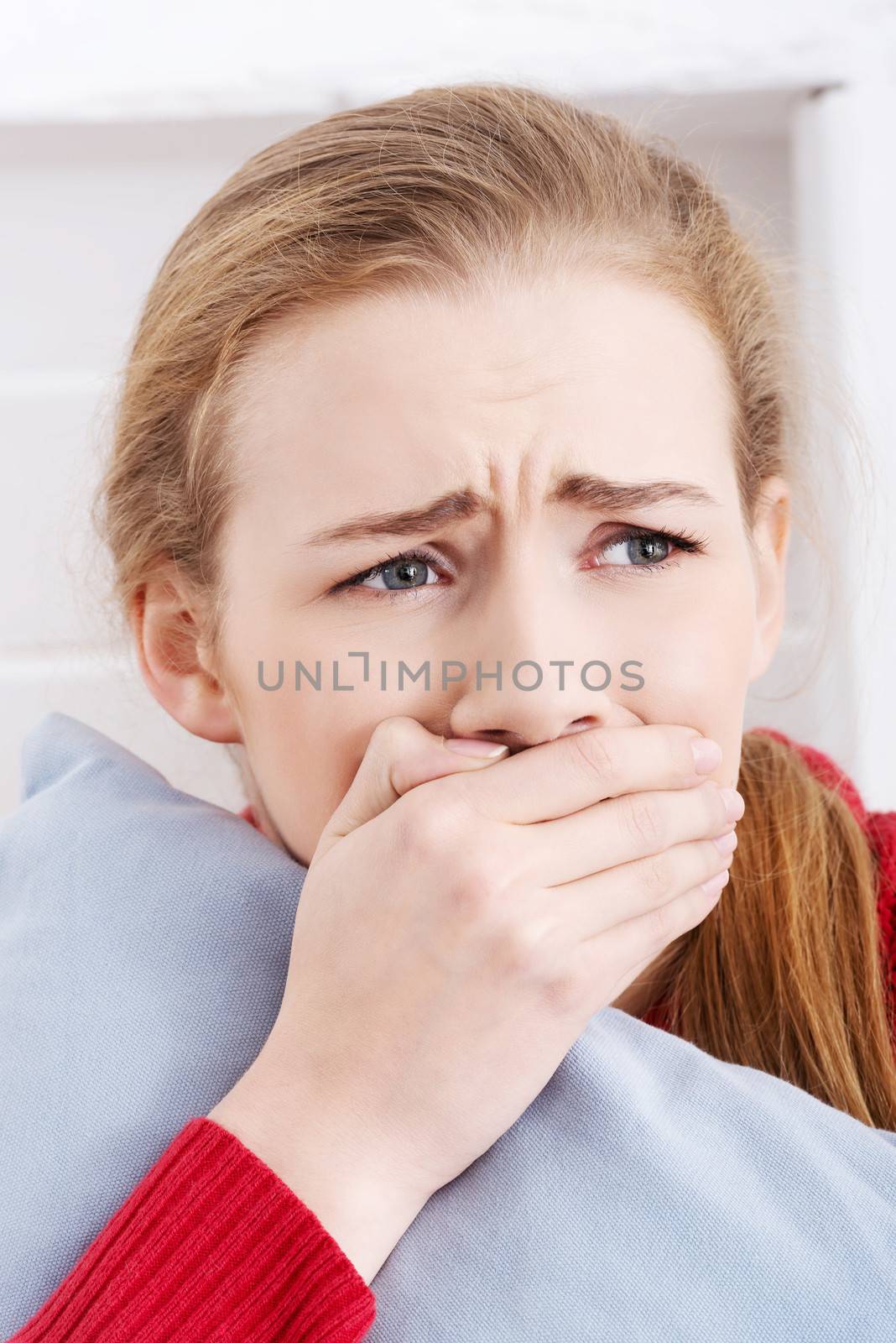 Sad or worried caucasian woman with pillow. Indoor background.