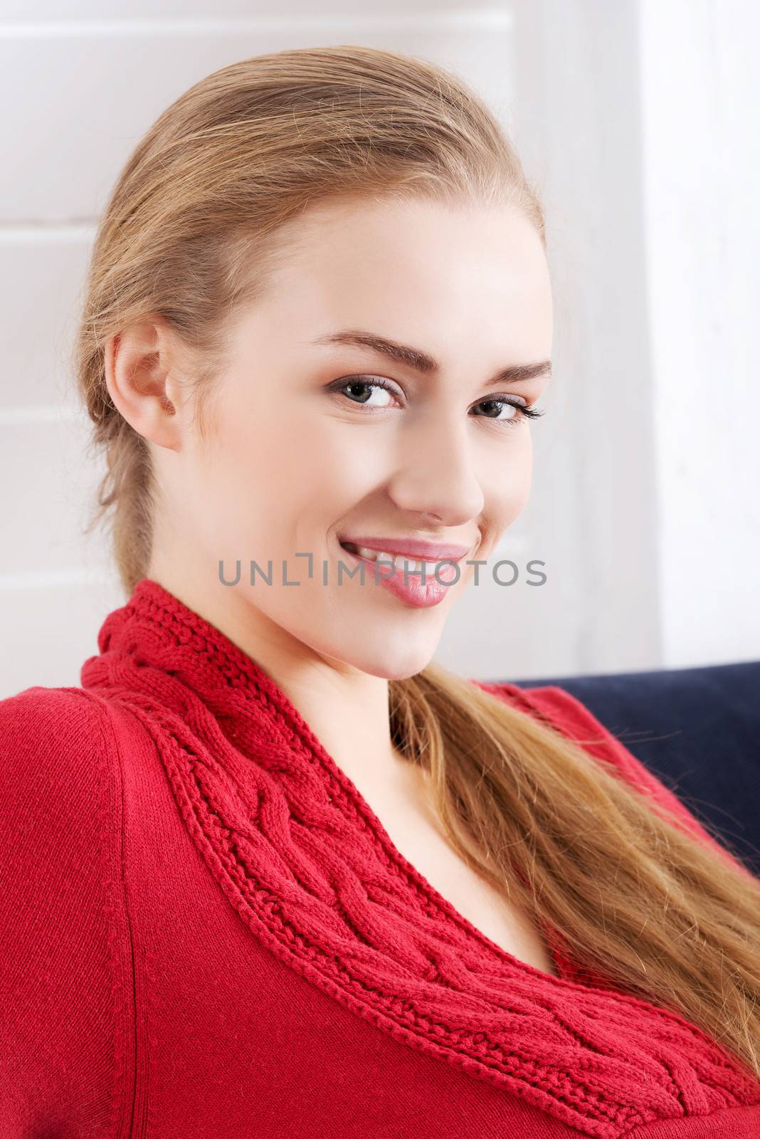 Beautiful caucasian woman sitting ona couch and wearing red pull by BDS