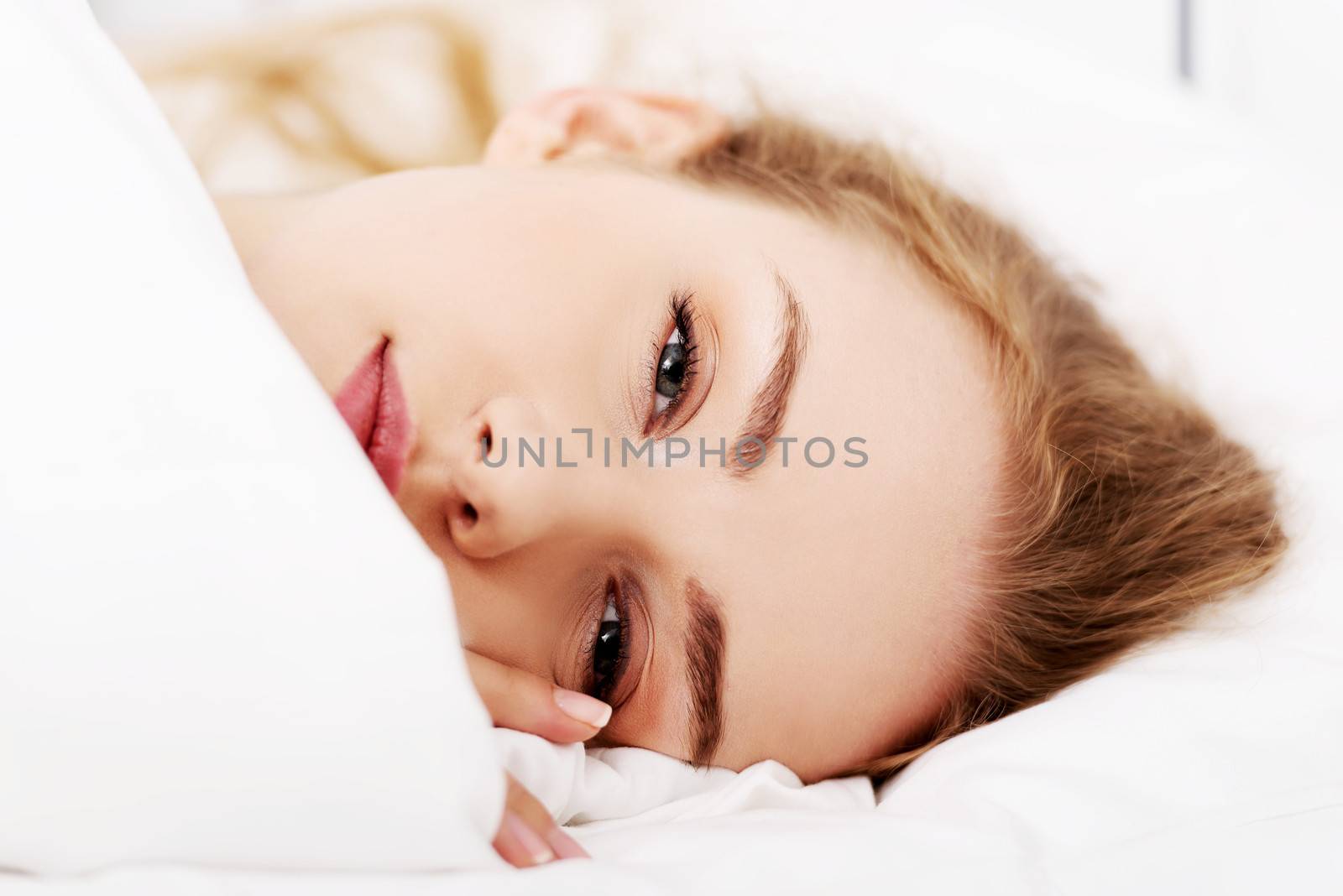 Beautiful caucasian woman lying in bed over white