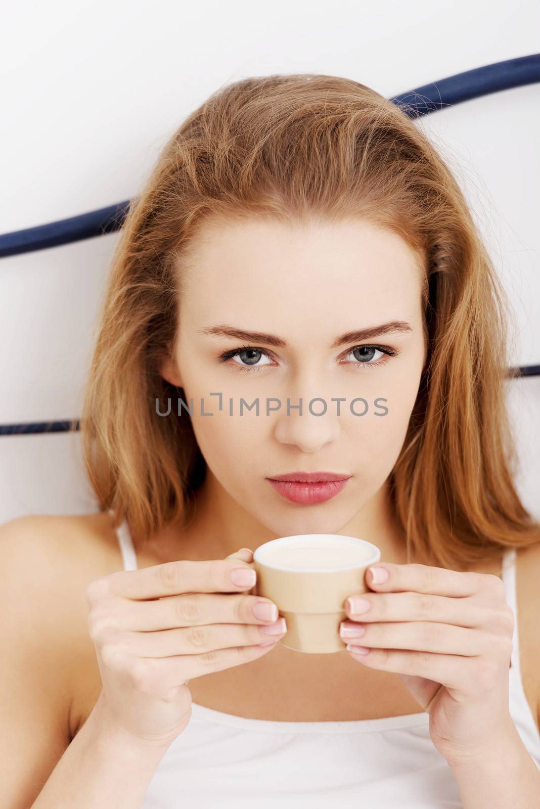 Beautiful caucasian woman in white lingerie is drinking small co by BDS