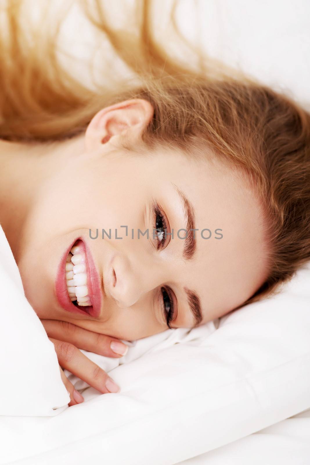 Smiling happy woman lying in bed. by BDS