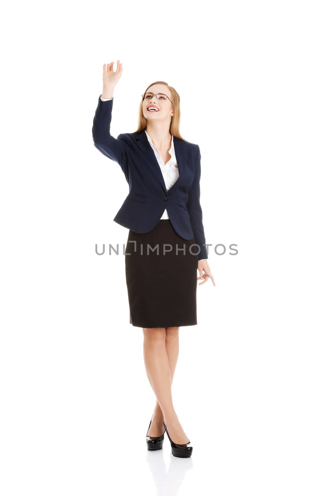 Beautiful business woman is touching an abstract space above her. Isolated on white.