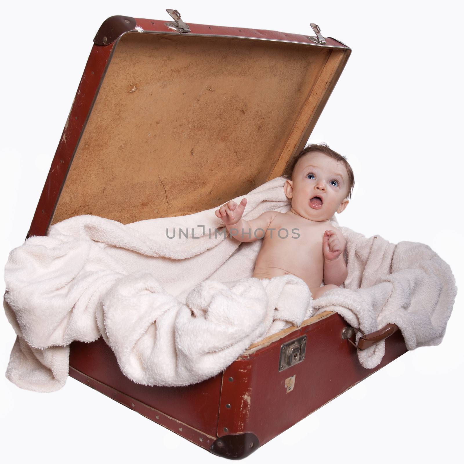 Little baby boy sitting naked on a blanket, in the old suitcases, on a white background