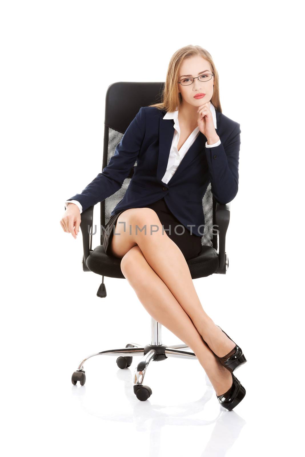 Beautiful caucasian business woman is sitting on a chair with her legs stretched. Isolated on white.