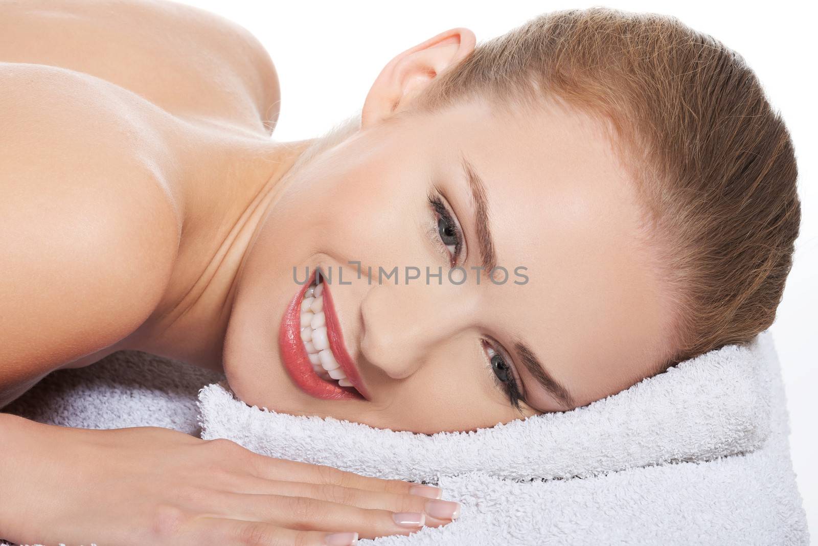 Beautiful caucasian woman is lying on massage table and relaxing. Isolated on white.