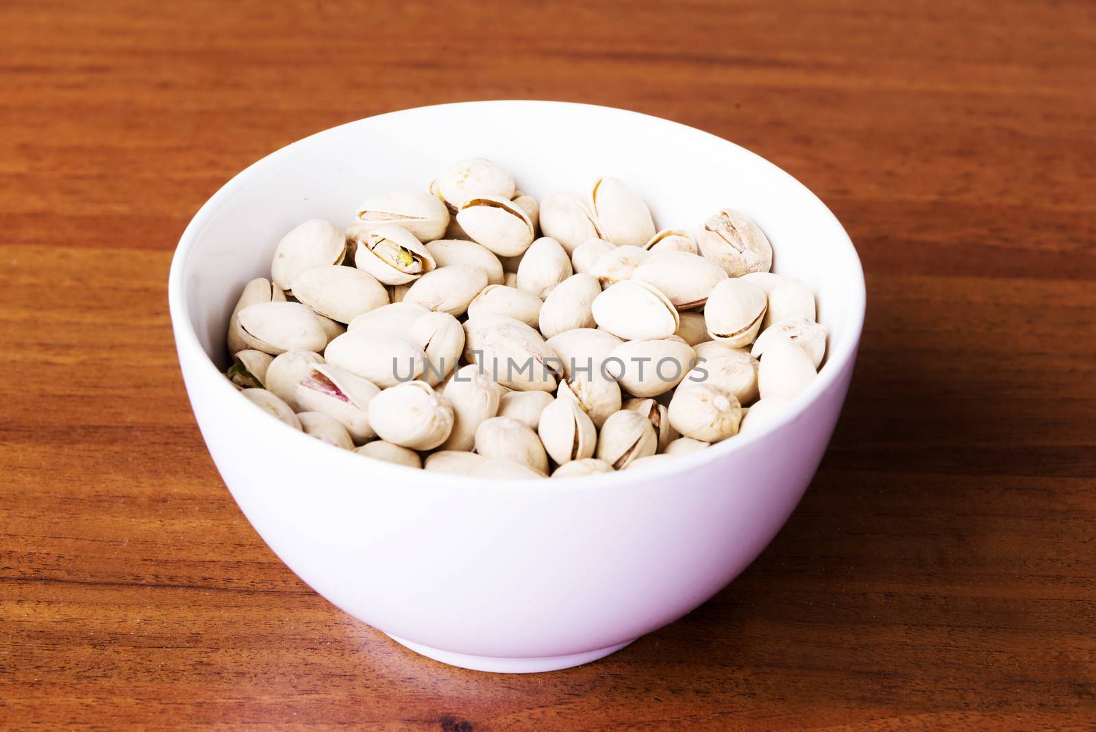 Pistachio in a bowl over wooden bacnground.