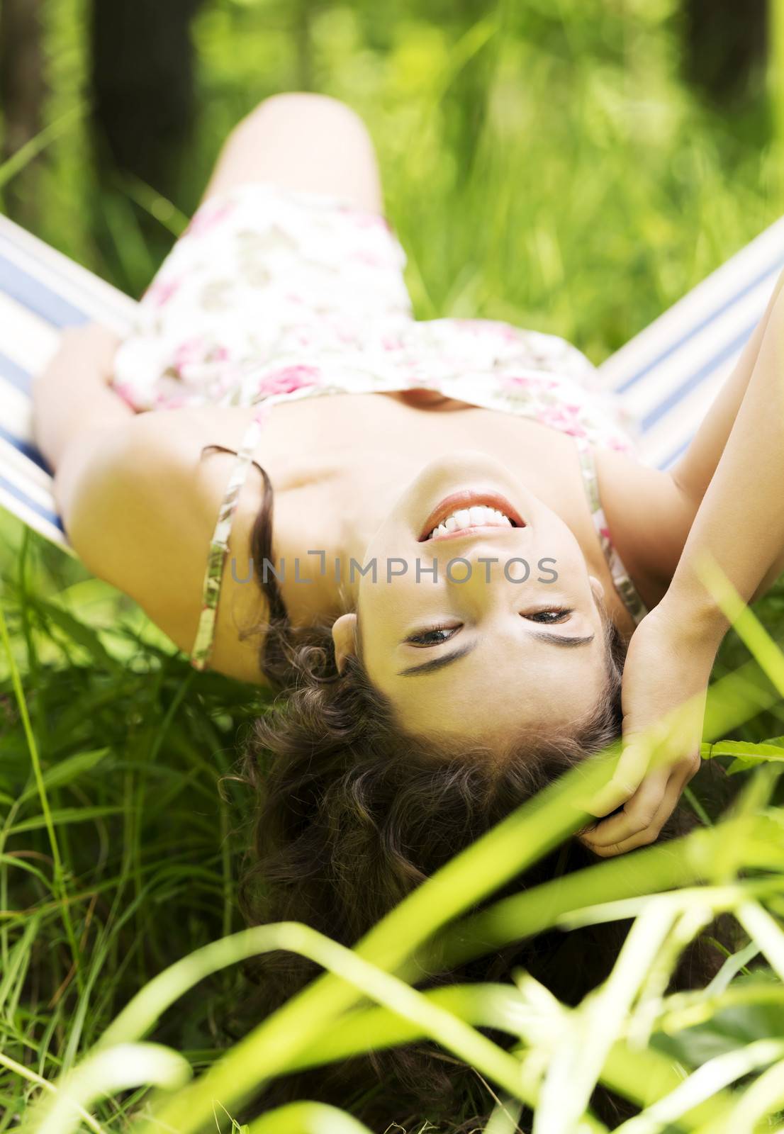 Young beautiful woman lying and relaxing in a hammock over sunny day.