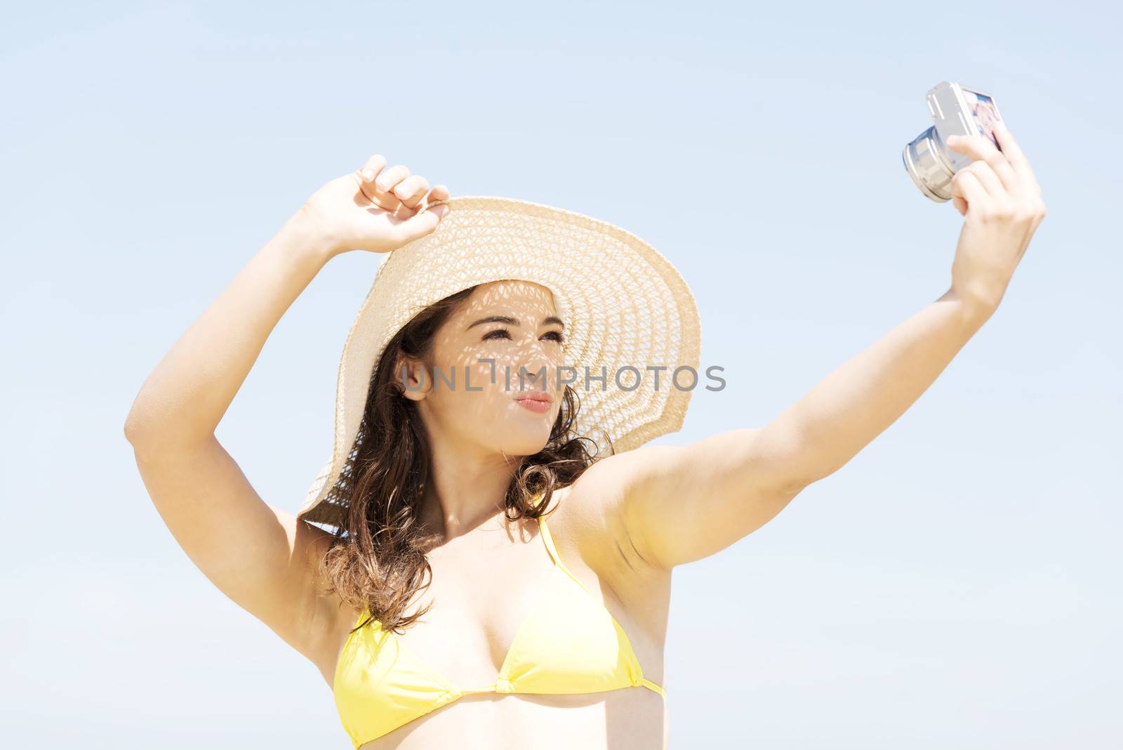 Beautiful young woman in a hat and swimsuit over seaside sunny day background.