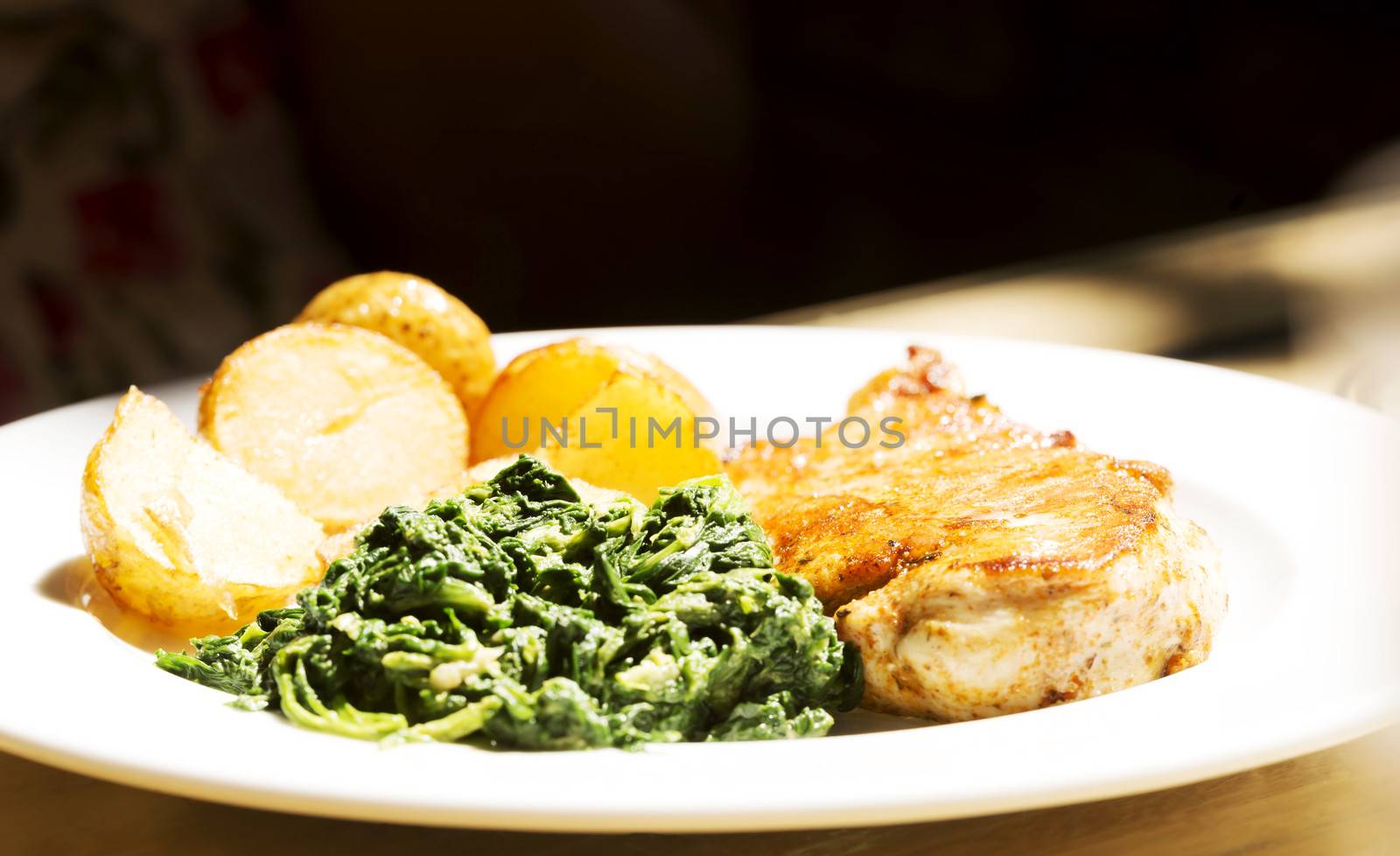 Fresh coocked food on a plate with spinach saland, potatoes and meat.