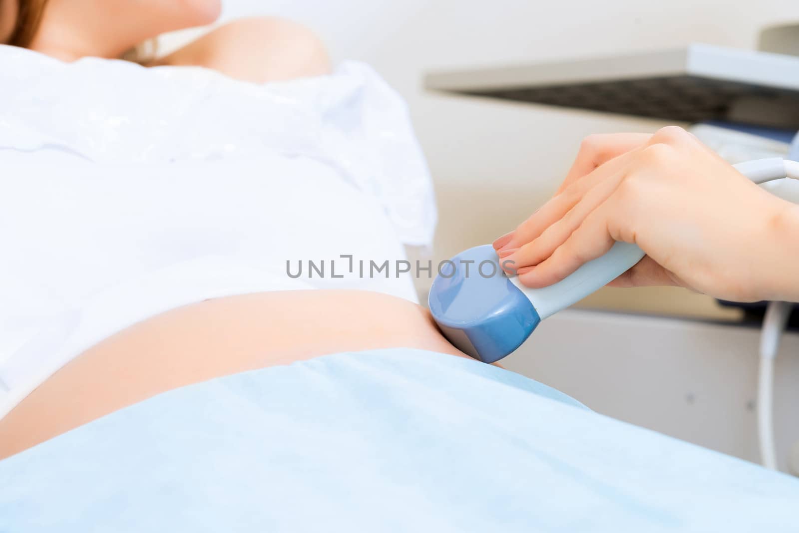 close-up of hands and abdominal ultrasound scanner for pregnant women