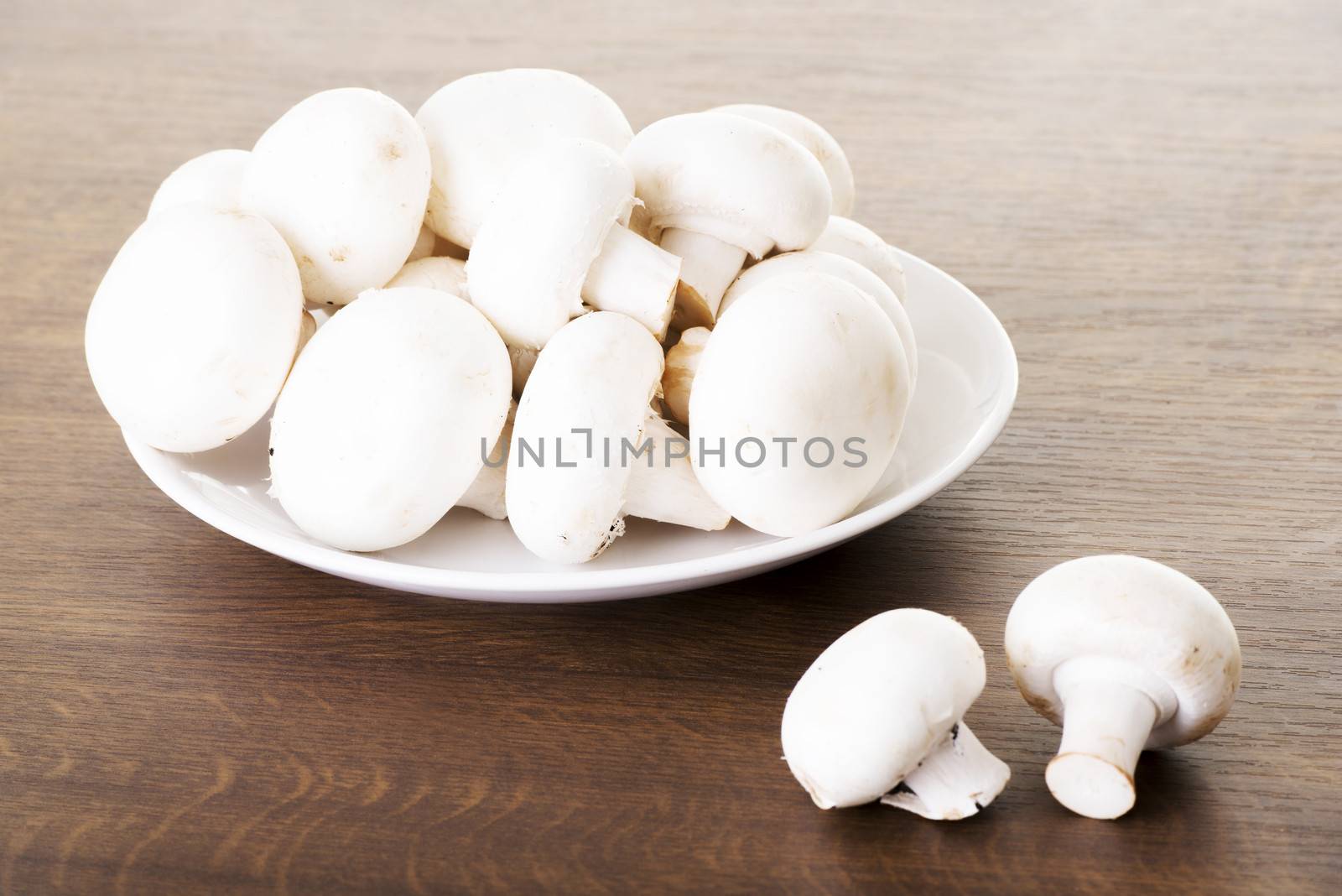 Fresh raw mashroom lying on a plate. Over wooden background.