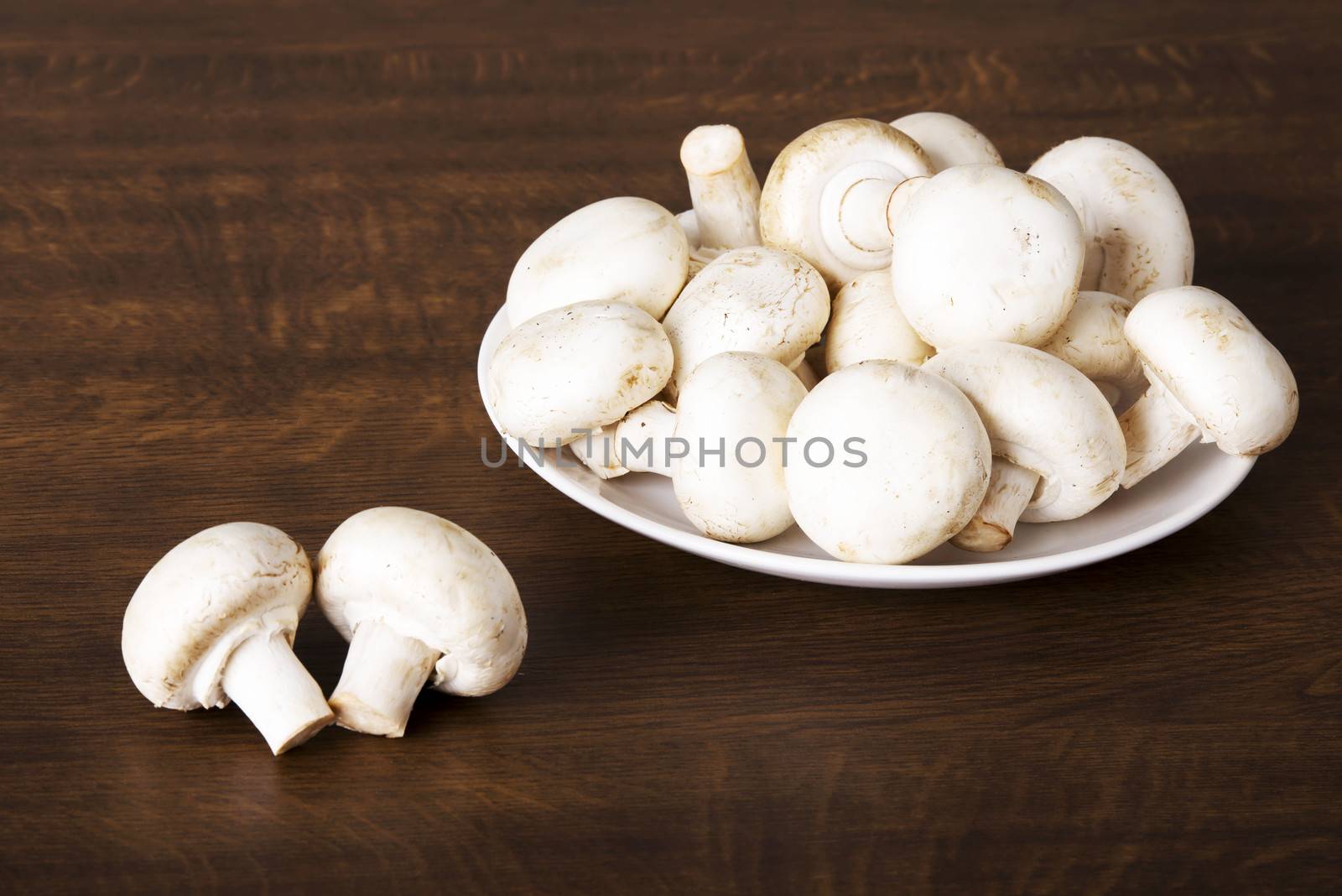 Fresh raw mashroom lying on a plate. Over wooden background.