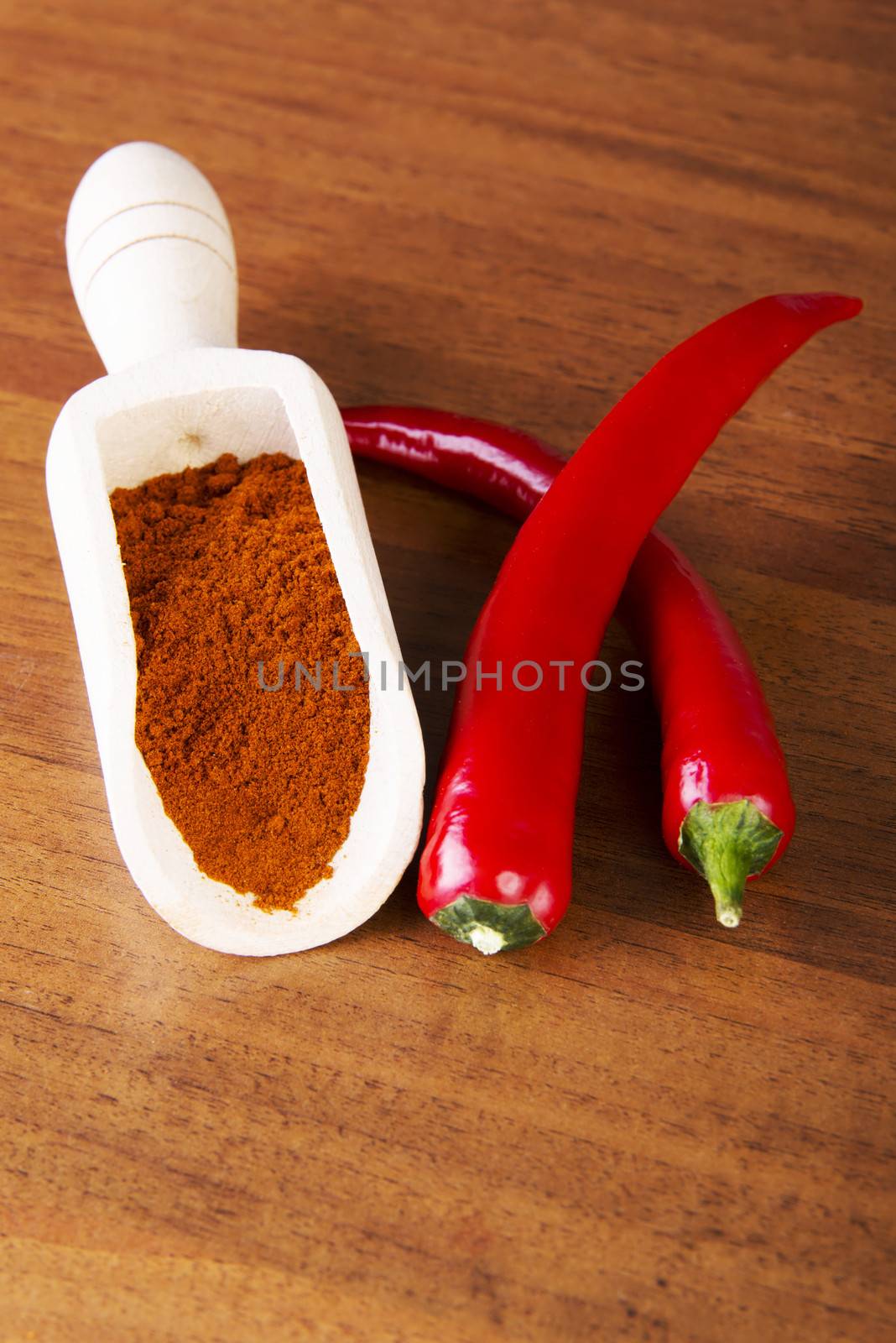 Two chili peppers with paprika spice lying on kitchen table.