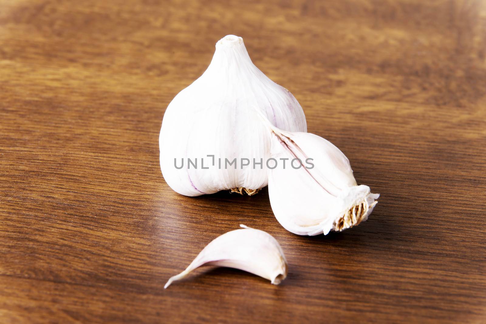Fresh raw garlic lying on a wooden table.