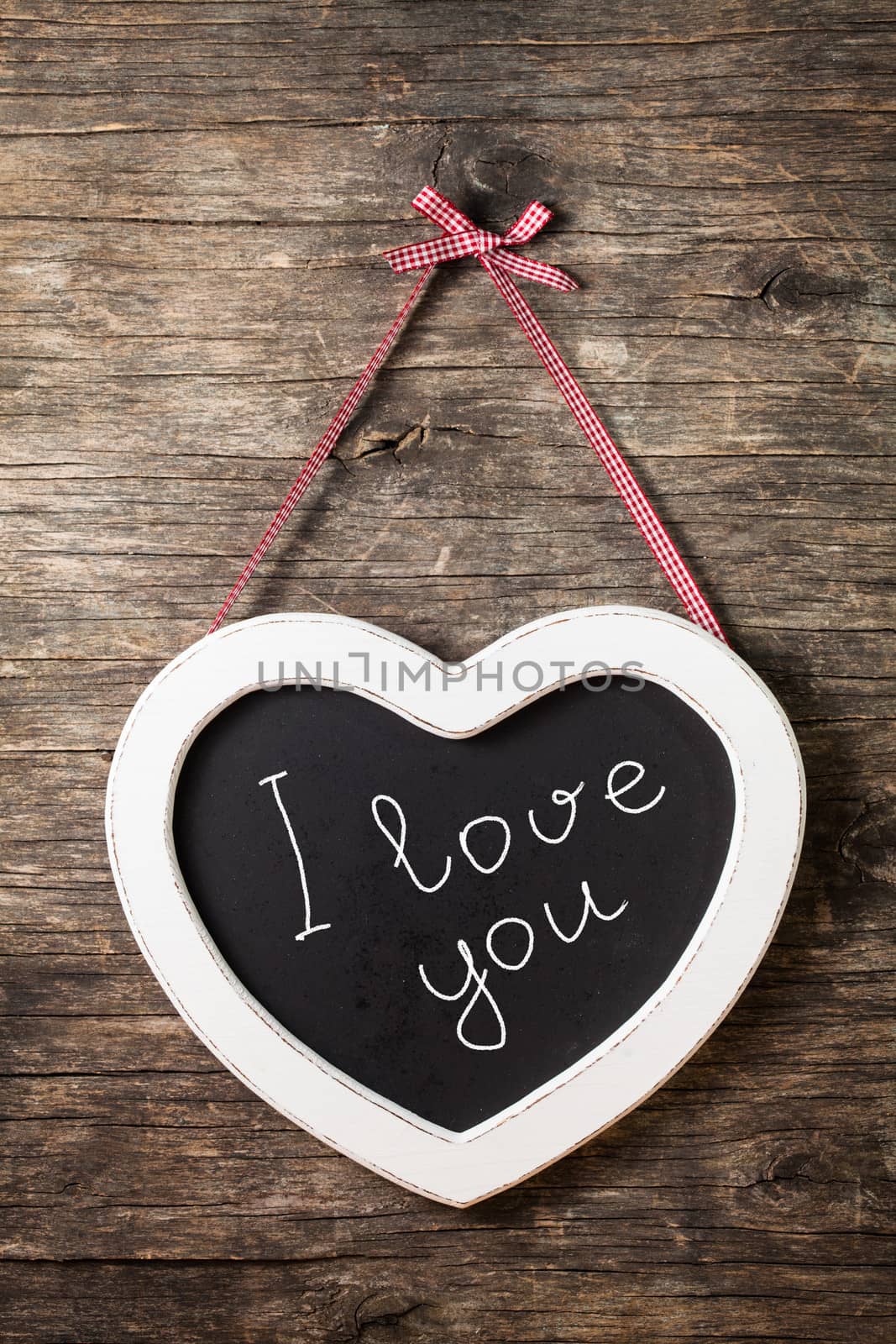 The heart shape chalkboard over old wooden background