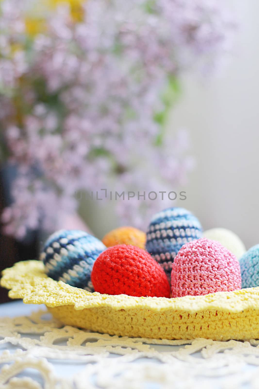 Basket of handmade knitted Easter eggs and lilac flower