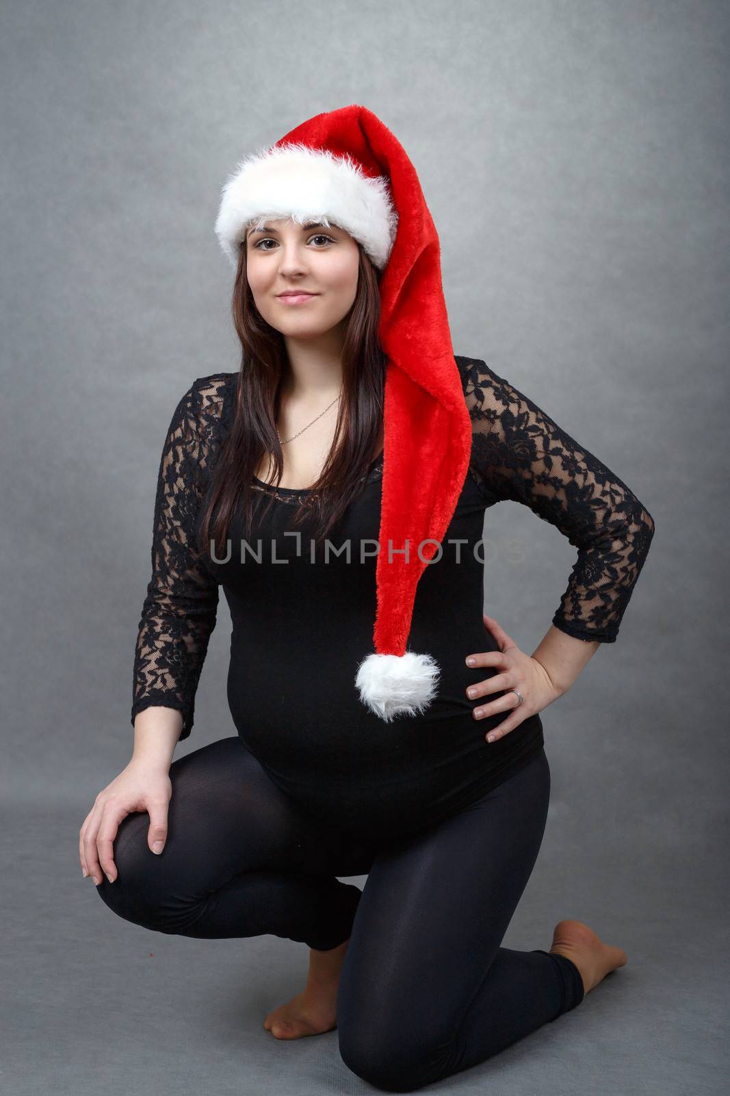 beautiful smiling pregnant young santa woman tenderly holding her tummy