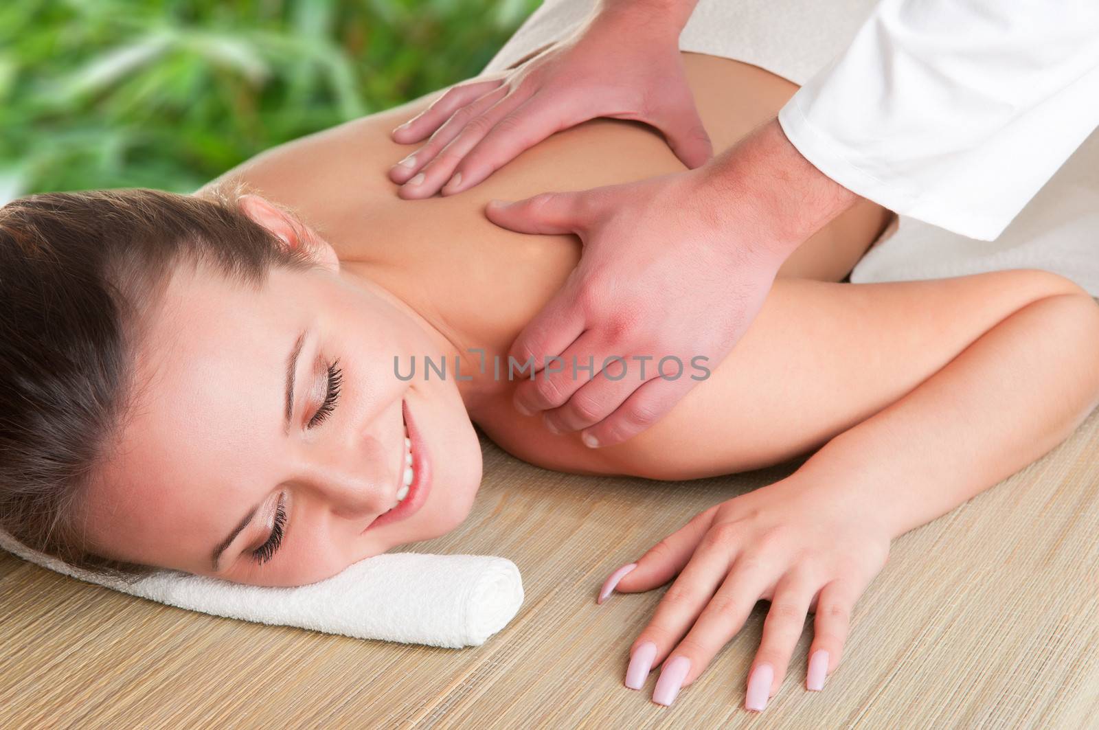 Young woman lying in a spa getting a massage, isolated in white