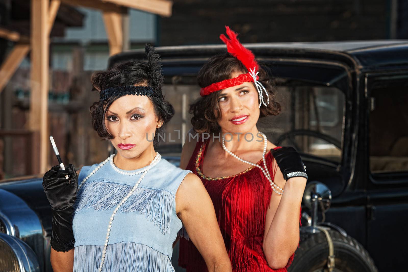 1920s flapper girls with cigarette near vintage automobile