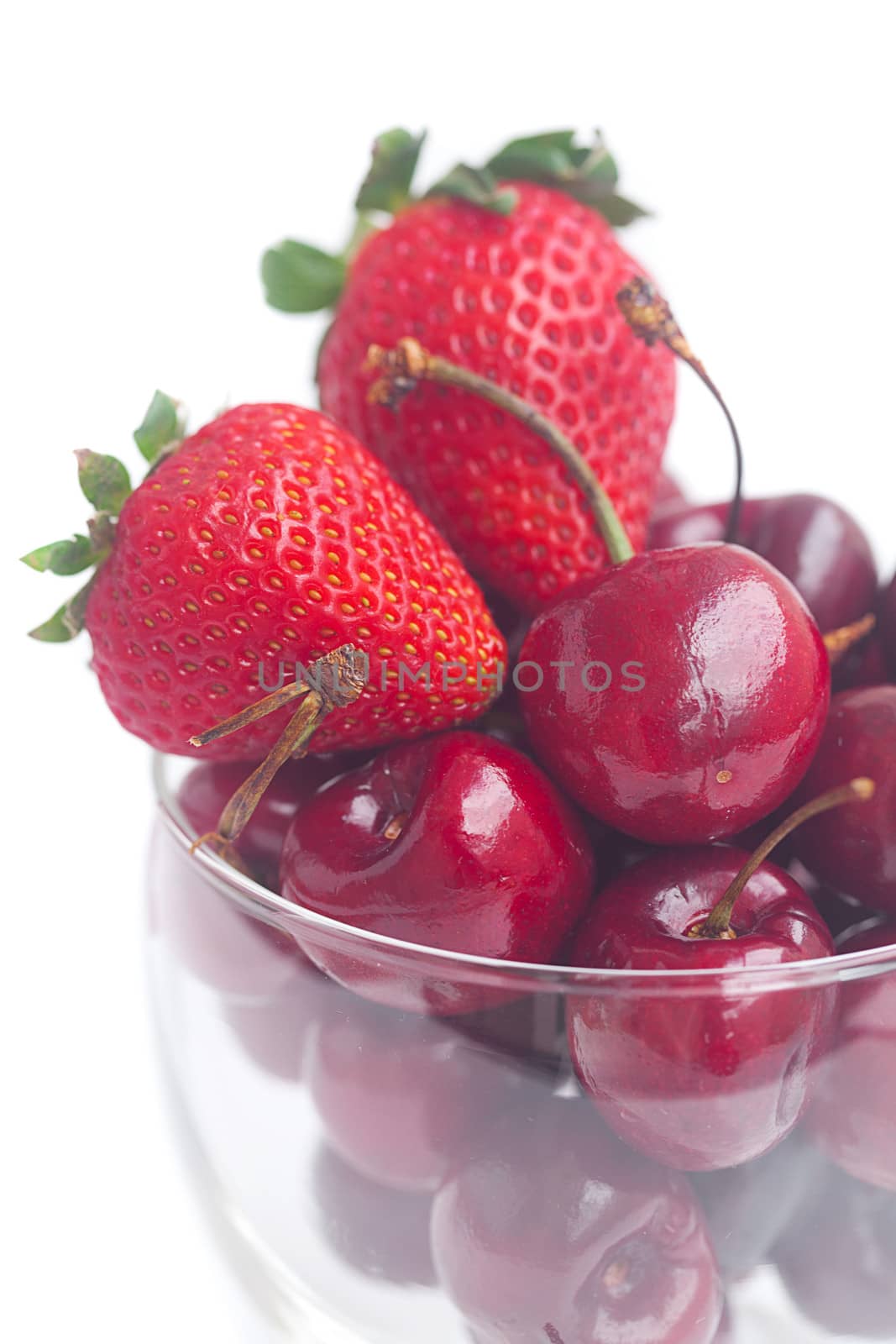 Cherries and strawberry in a glass bowl isolated on white by jannyjus